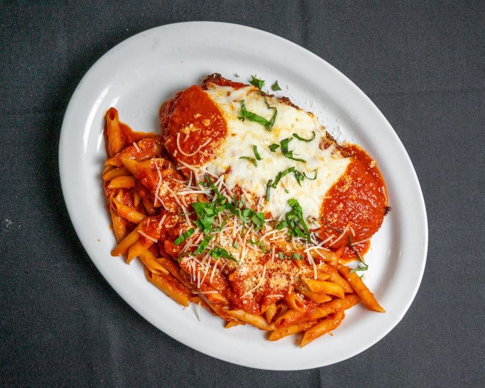Chicken parmesan with penne pasta, marinara sauce, melted mozzarella, and fresh basil.